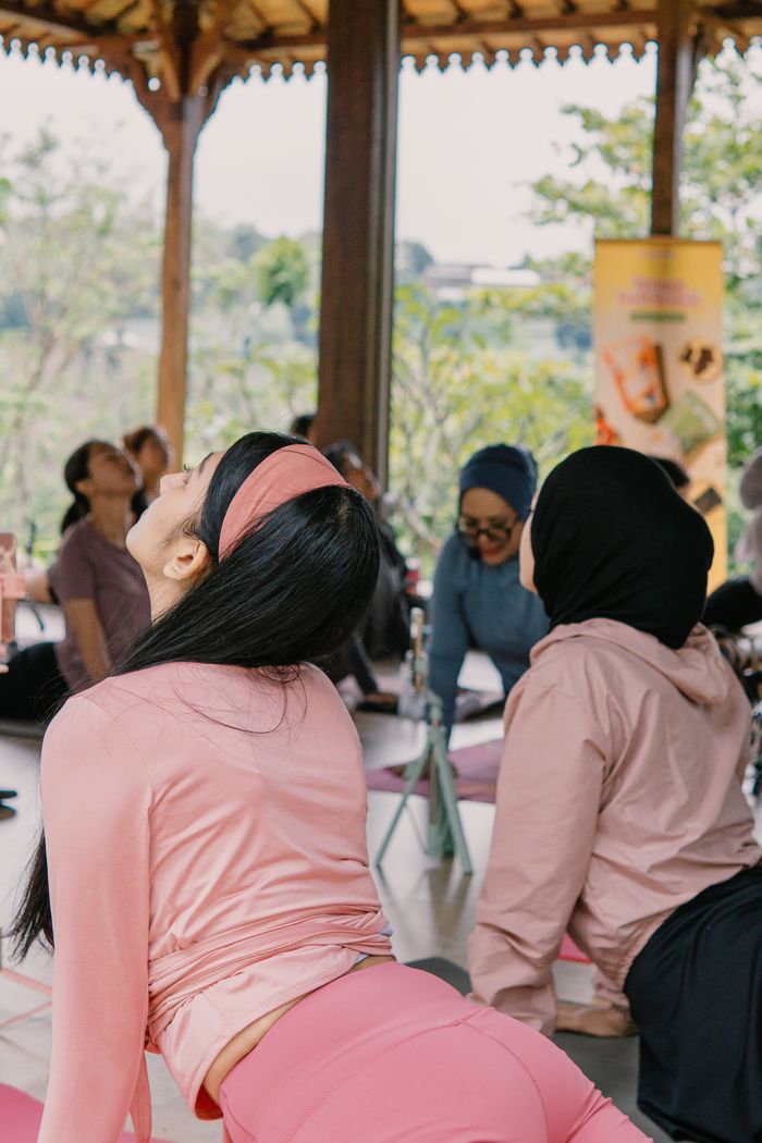 Women practicing yoga outdoors under a traditional pavilion in Jawa Barat, Indonesia.